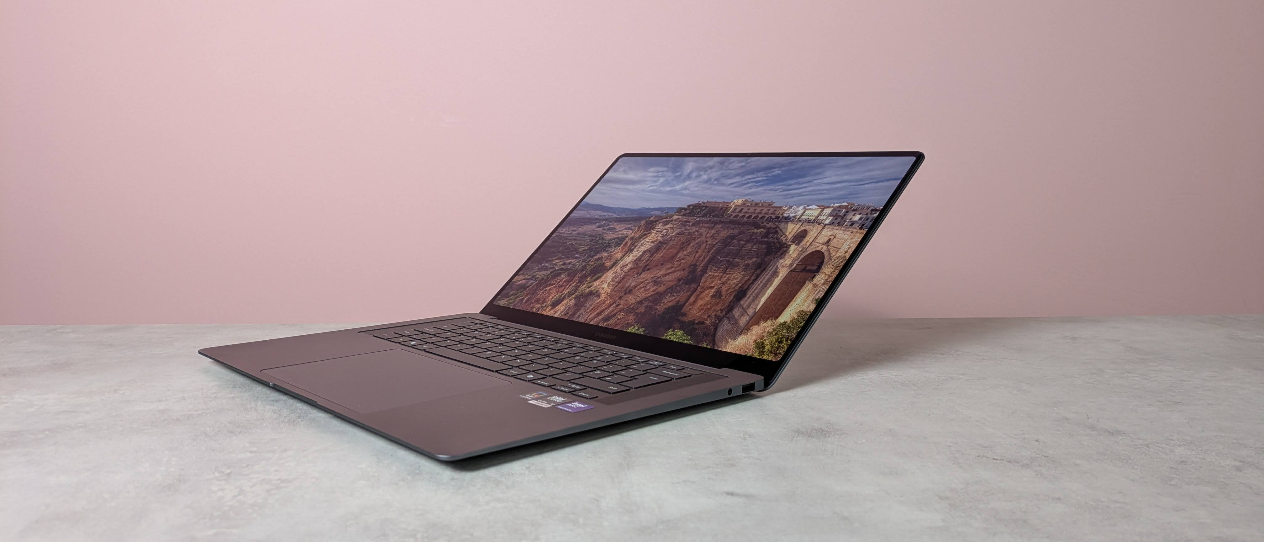 Three-quarter view of Samsung Galaxy Book6 Pro open on white desk with pink wall in background