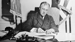 FDR signing a paper on his desk