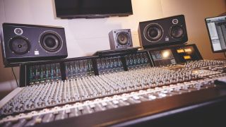 A studio desk with multiple studio monitors on top of it