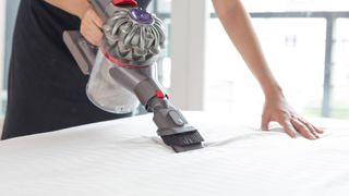 Person using a handheld vacuum to show how to clean a mattress thoroughly
