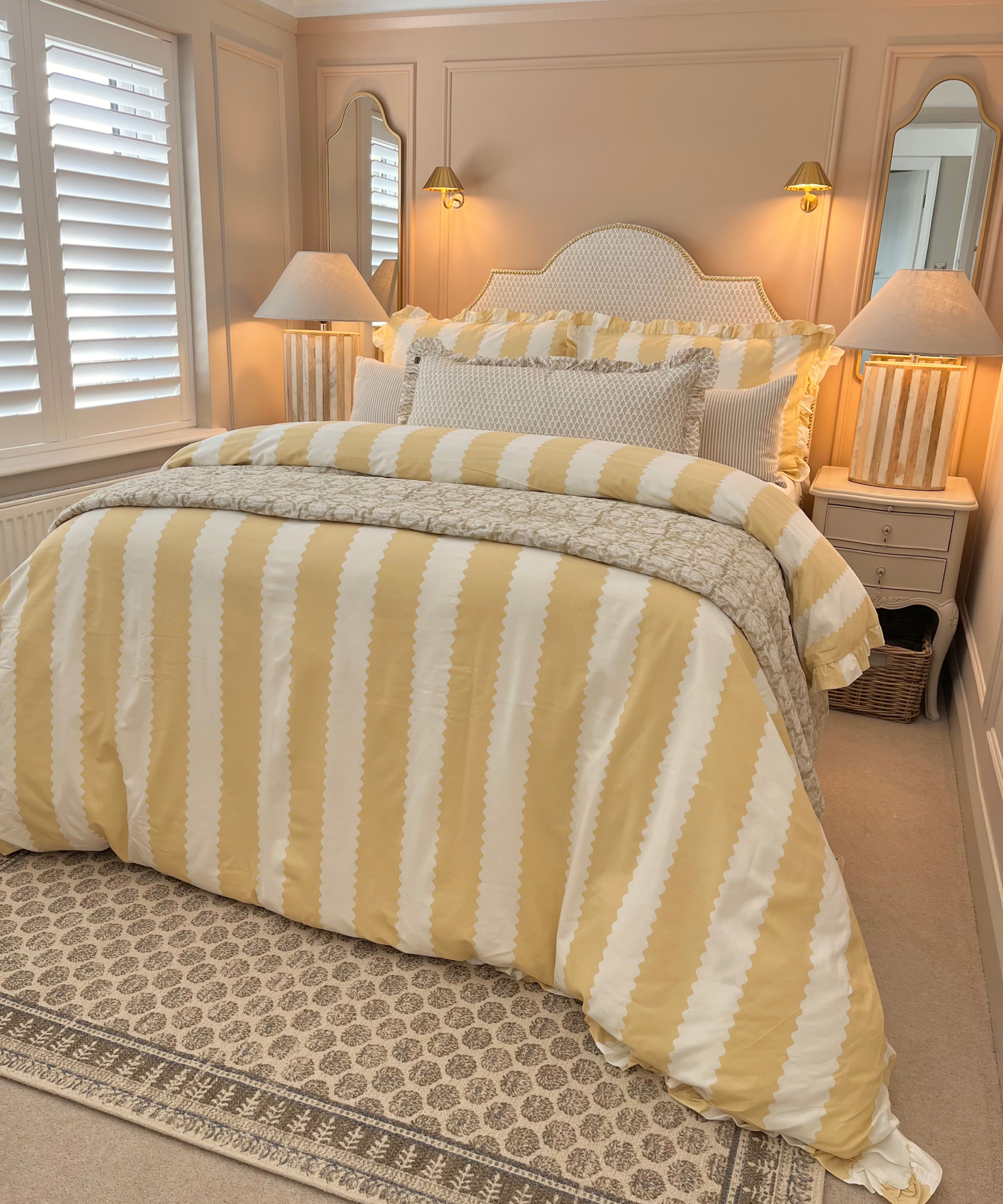 small bedroom with mirrors behind bedside tables reflecting light of two bedside lamps