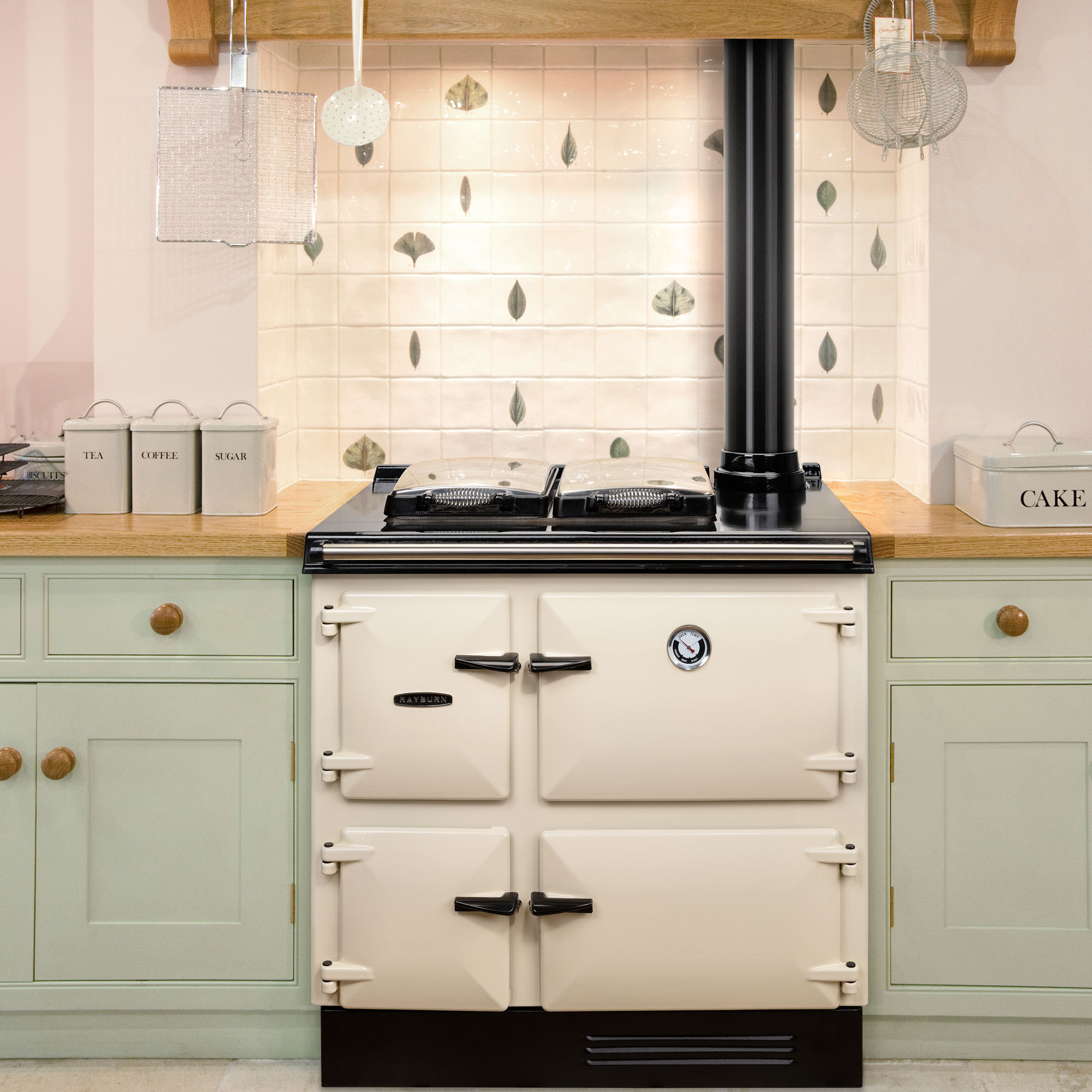 Cream range cooker with green kitchen cabinets and a tiled splashback