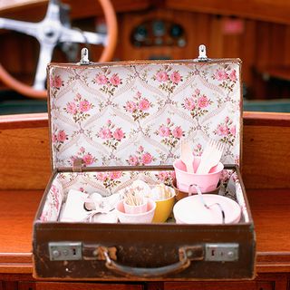 vintage suitcase with pretty floral fabric and doilies and ribbon tied cutlery
