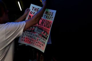 A man holding up a poster to hang on a line in a workshop