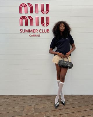 Woman wearing polo top and preppy skirt at a Miu Miu event.