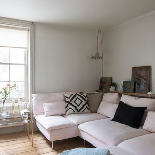 Sitting room with wooden floors, light pink sofa and cushions