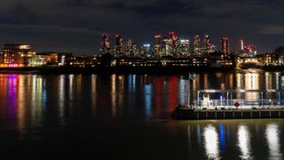 Looking at tall buildings of Canary wharf at night across the thames river