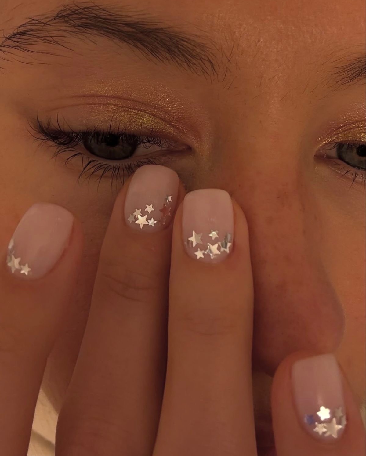 close-up of short nude nails scattered with tiny silver stars