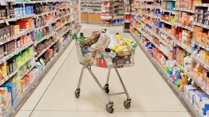 A full shopping cart in the middle of a supermarket aisle