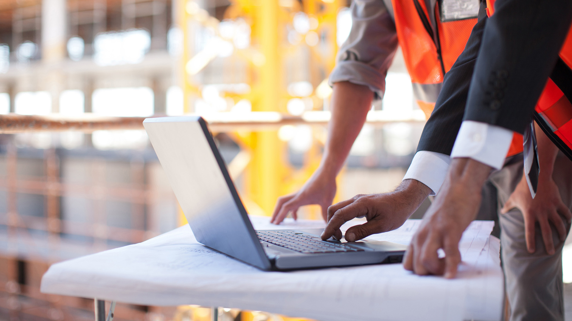Construction workers using a laptop on a construction site.