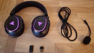 Image of the Razer X Chroma headset and all that comes with it on a wooden countertop, taken by author Rosalie Newcombe.