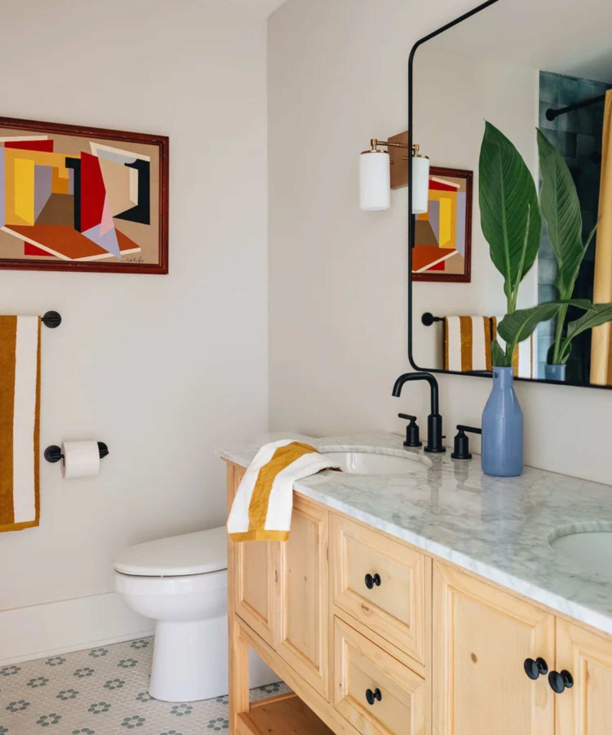 Neutral bathroom with wooden console, a black mirror above and colorful accessories