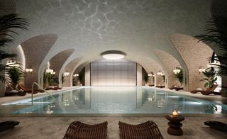 Indoor swimming pool surrounded by loungers with a curved ceiling above.