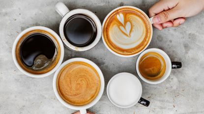 Directly Above Shot Of Hands Holding Coffee Cups On Table - stock photo