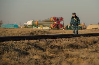 Guard Walks Along Tracks with the Soyuz rocket in the background.