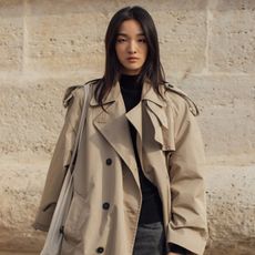 Woman in trench coat, black sweater, black jeans, and boots at Paris SS26 Fashion Week.