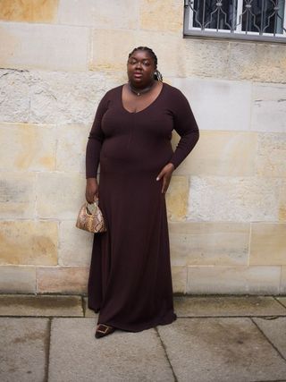 Woman wears burgundy maxi dress, snake handbag