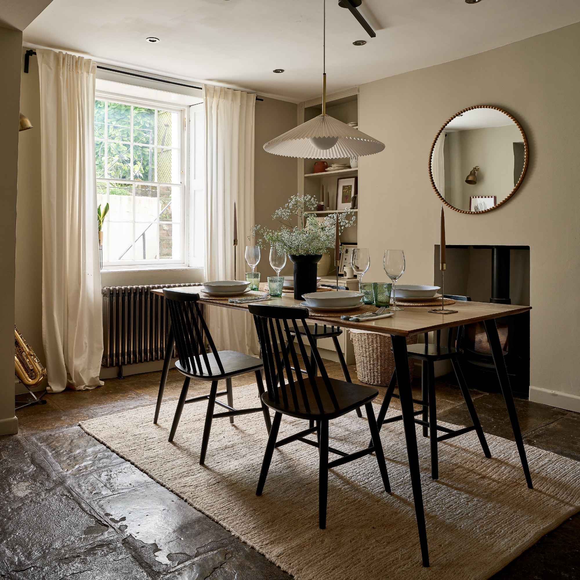 A beige-painted dining room with a rectangular dining table and windows dressed with full-length white curtains