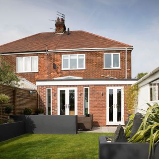 house with white windows and garden with patio table