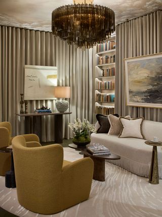 a beige room with a curtain wall, a wallpapered ceiling and chandelier, with artwork hung over the walls