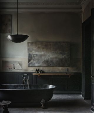 A moody industrial style bathroom with a black standalone bathtub