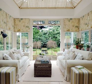 White conservatory with two cream sofas and floral blinds