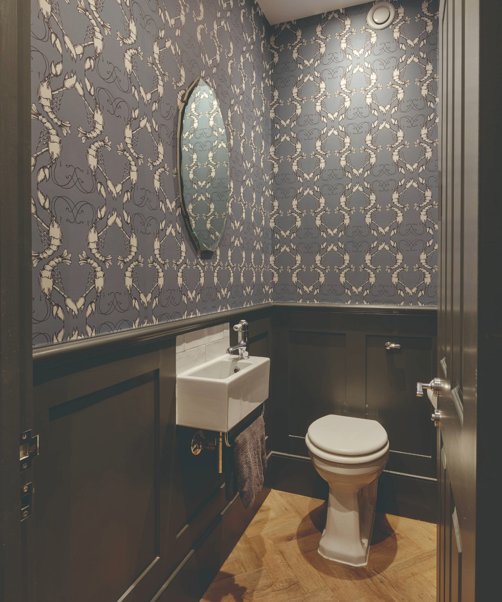 Toilet with small basin and wallpaper and panels