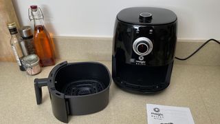 Magic Bullet Air Fryer on a counter with its user manual, tray removed and on display