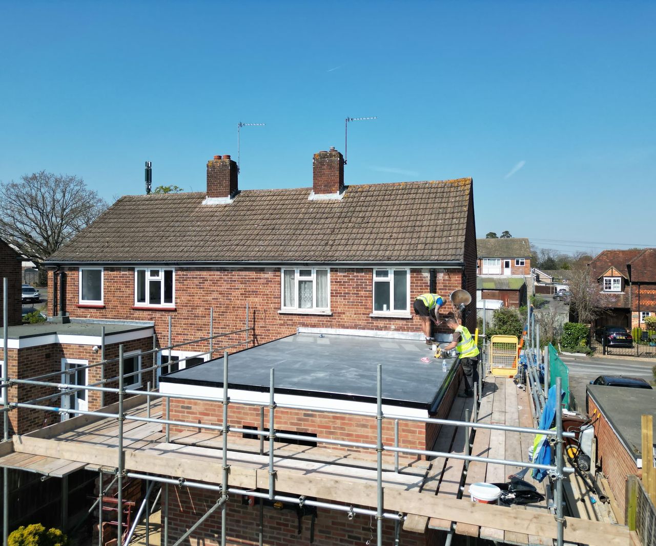 An extension with builders on the roof surrounded by scaffolding