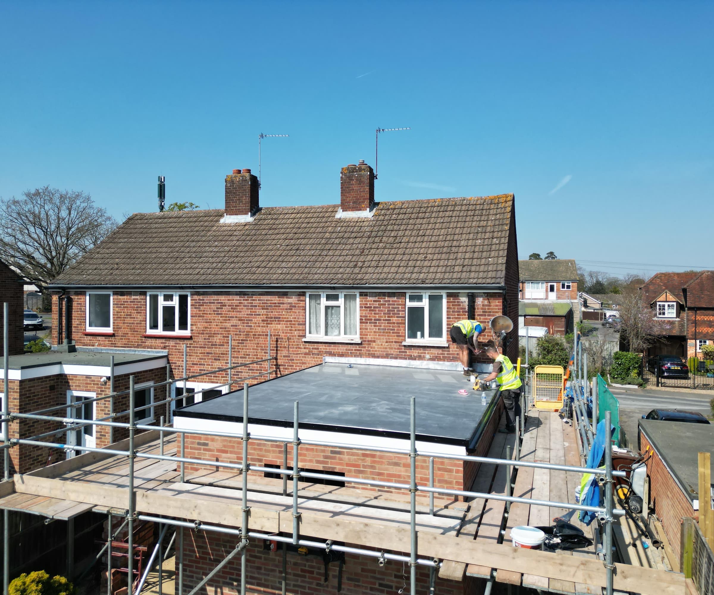 An extension with builders on the roof surrounded by scaffolding