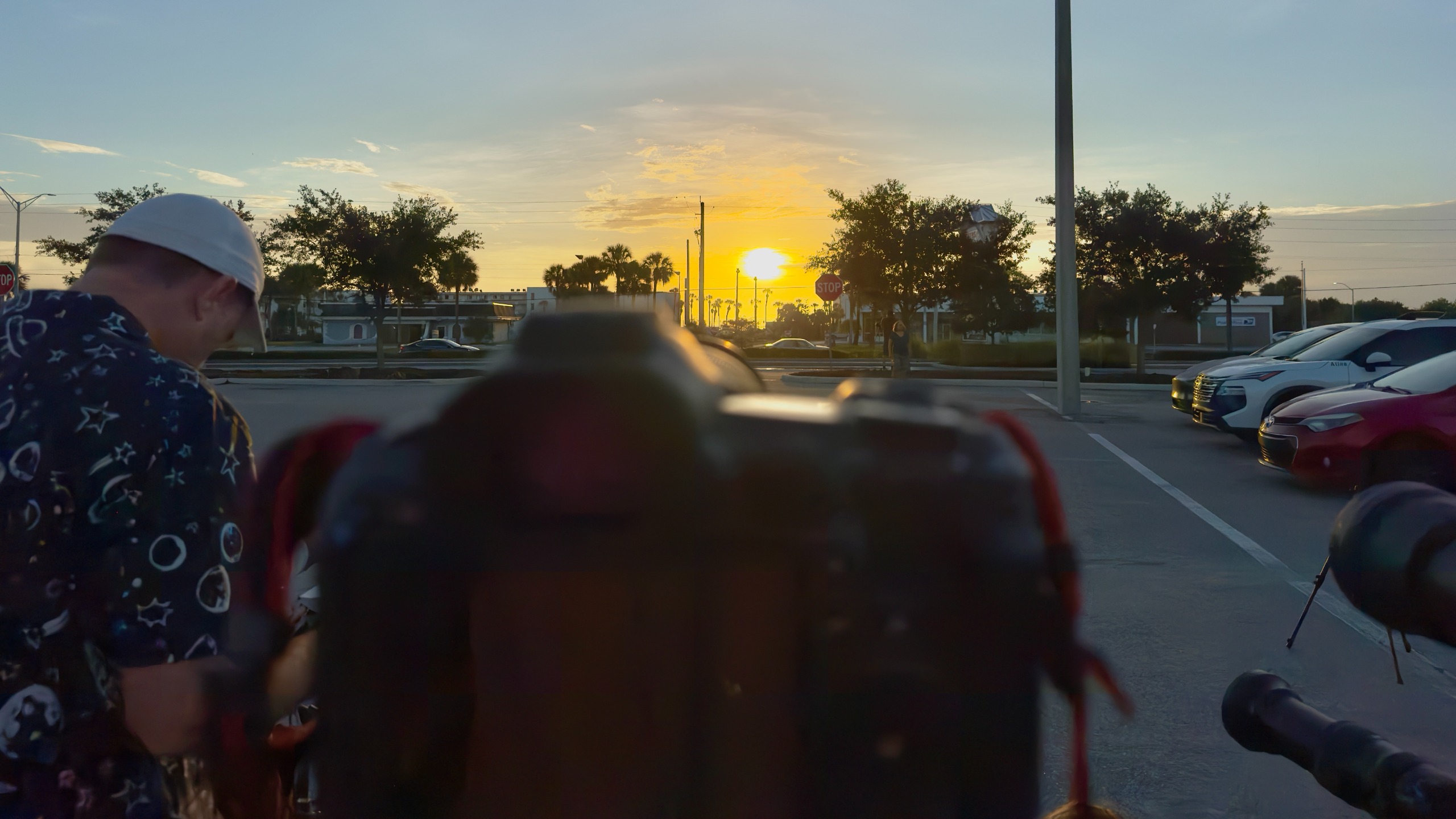 An out of focus camera in the foreground looks at the rising sun in the distance.
