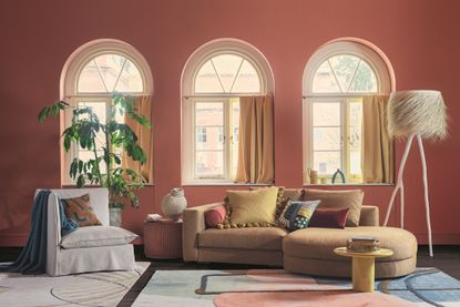 Soft red living room with chaise lounge below arched windows 