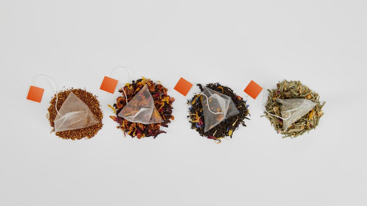 A row of four teabags with loose tea beneath them