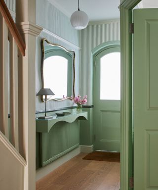 green small entryway with stripe wallpaper and statement mirror