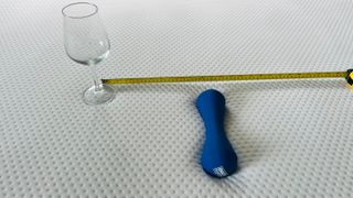 A wine glass, weight, and tape measure balanced on the surface of the Emma NextGen Cooling mattress, demonstrating motion isolation