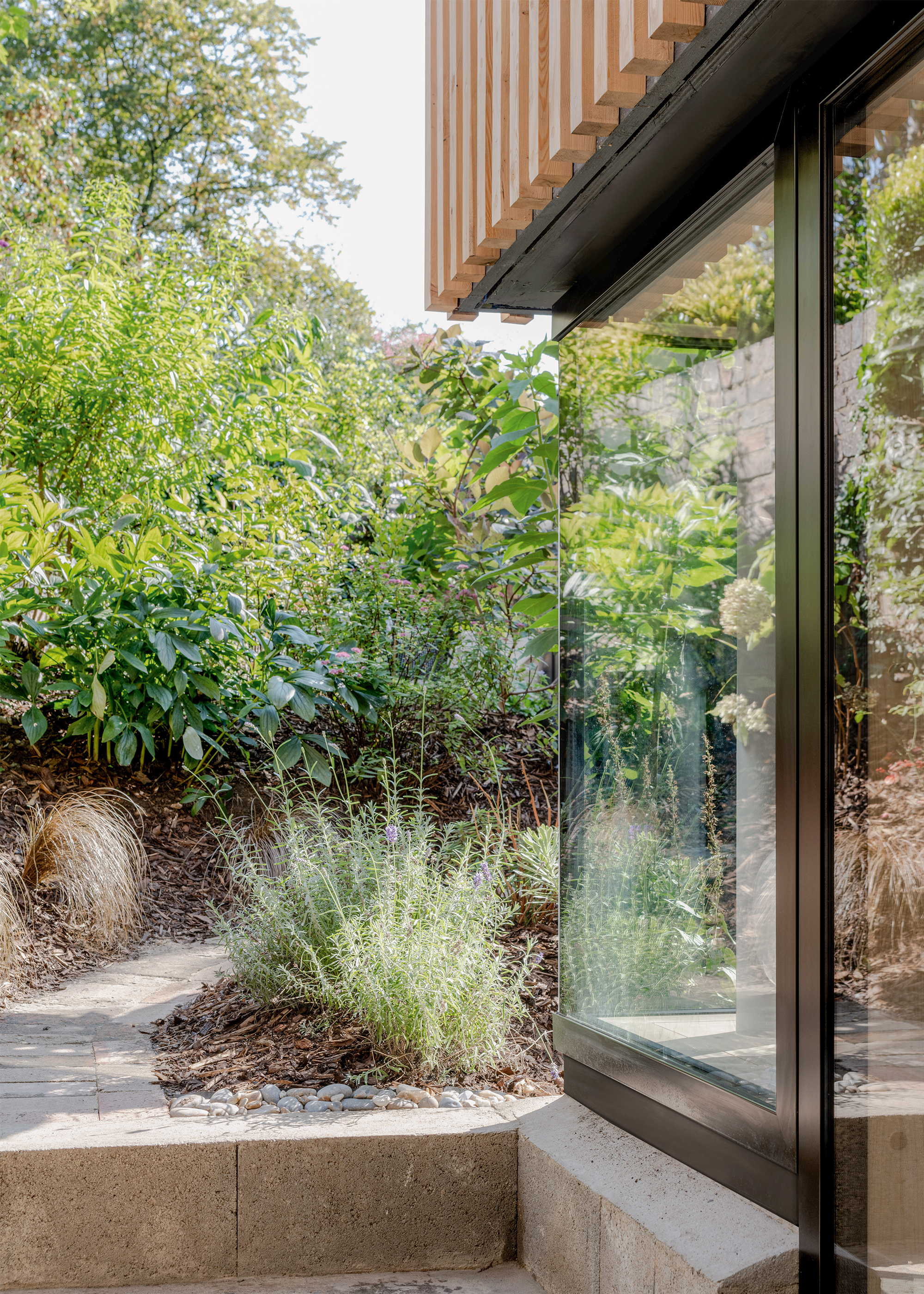 A large window looks out on a stone path which winds through green borders.