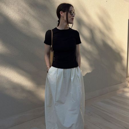 Woman wears black t-shirt, white skirt