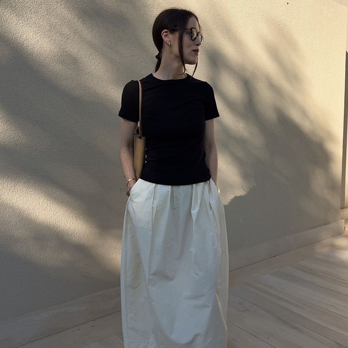 Woman wears black t-shirt, white skirt