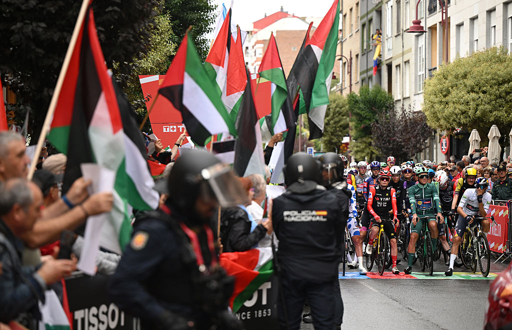 O BARCO DE VALDEORRAS, SPAIN - SEPTEMBER 10: (L-R) Jonas Vingegaard of Denmark and Team Visma | Lease a Bike - Red Leader Jersey, Mads Pedersen of Denmark and Team Lidl - Trek - Green Points Jersey and Giulio Pellizzari of Italy and Team Red Bull - BORA - hansgrohe - White Best Young Rider Jersey while a group of fans protest displaying Palestinian flags prior to the La Vuelta - 80th Tour of Spain 2025, Stage 17 a 143.2km stage from O Barco de Valdeorras to Alto de El Morredero 1755m / #UCIWT / on September 10, 2025 in Alto de O Barco de Valdeorras, Spain. (Photo by Dario Belingheri/Getty Images)