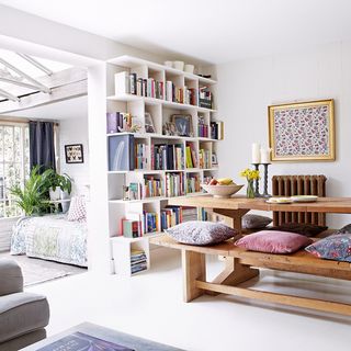 white living room with book shelf and wooden table
