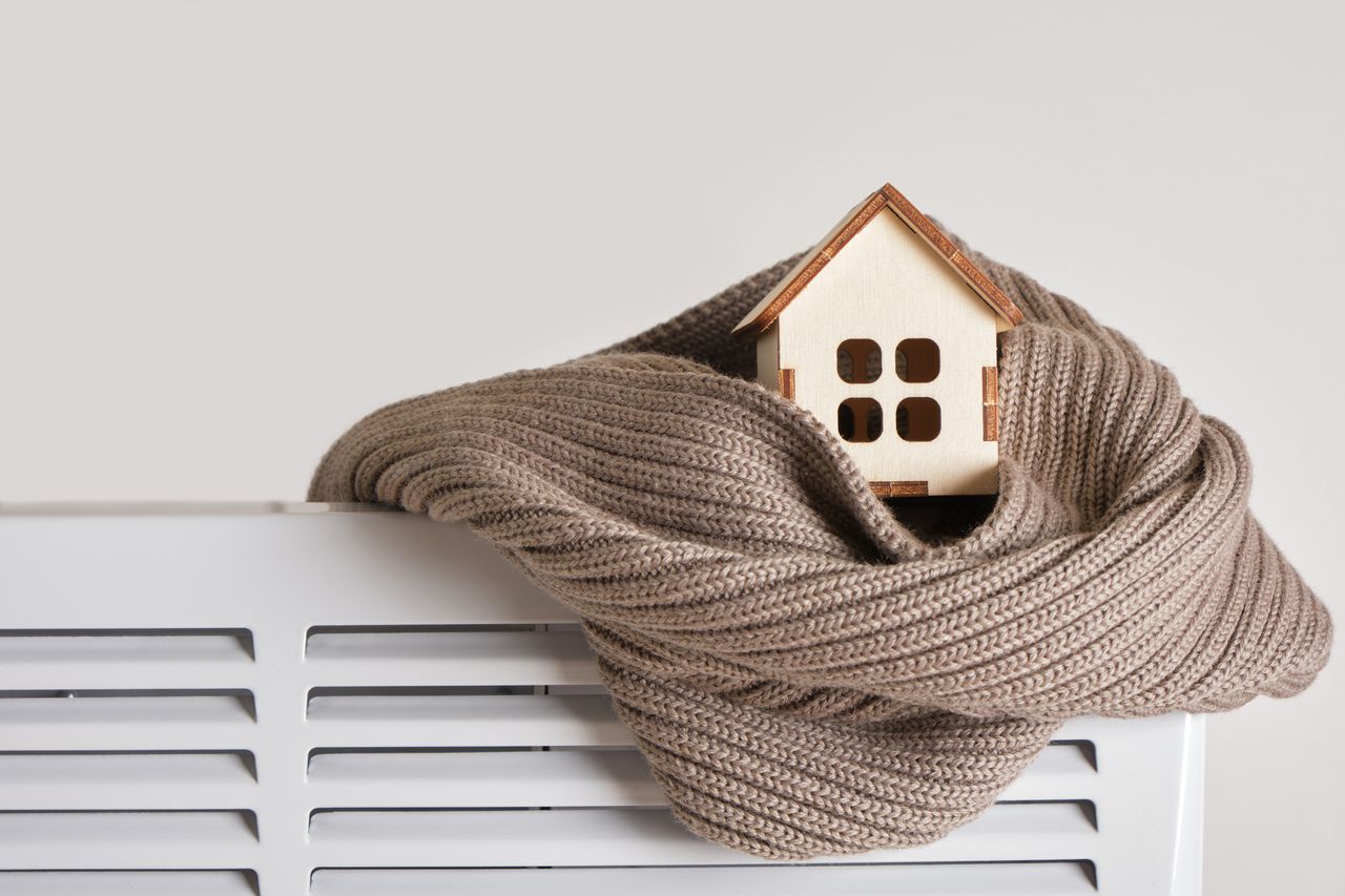 little wooden house wrapped in brown scarf on a radiator