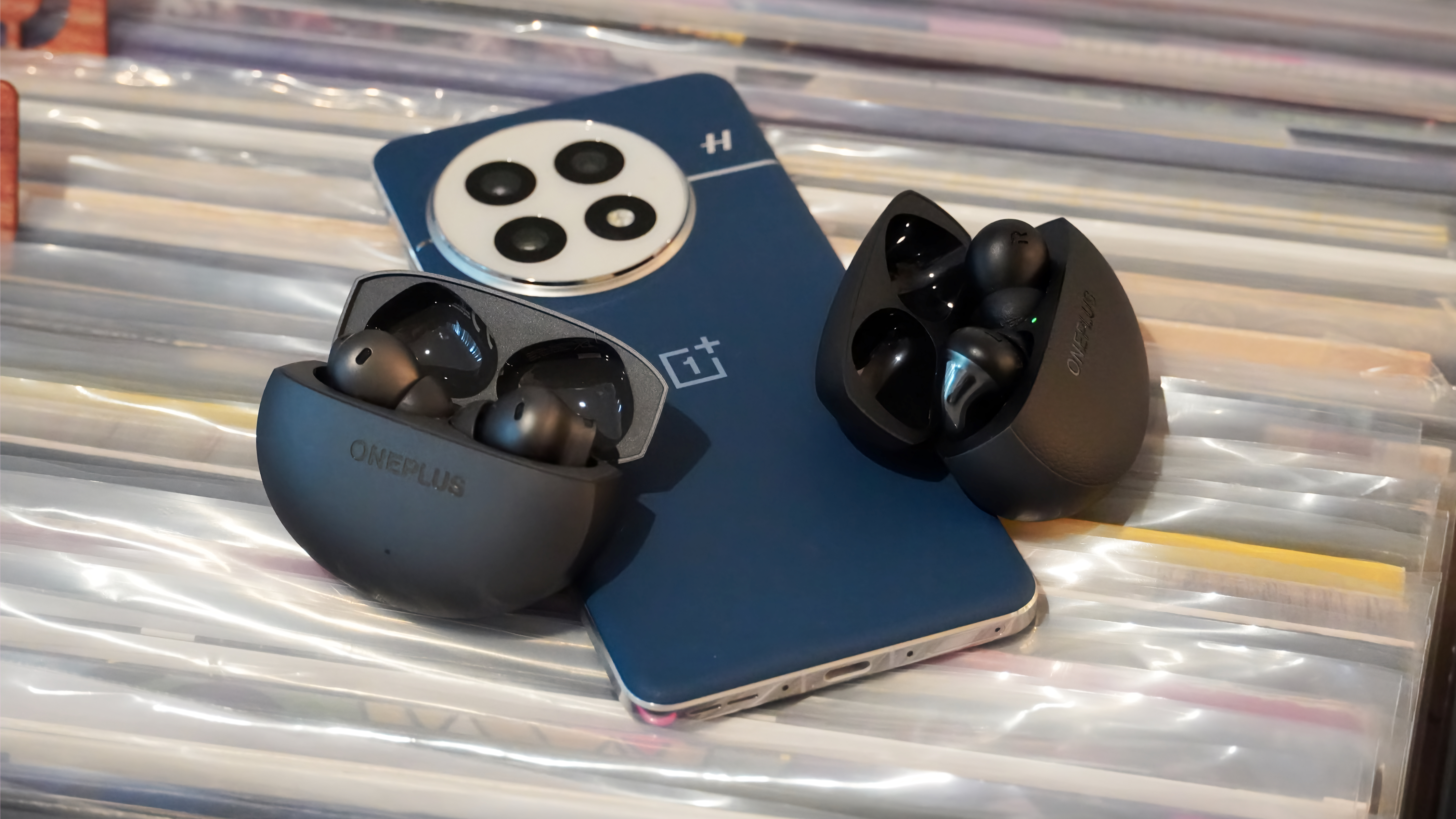 The OnePlus Buds 4 with the OnePlus Buds Pro 3 on top of a OnePlus 13.