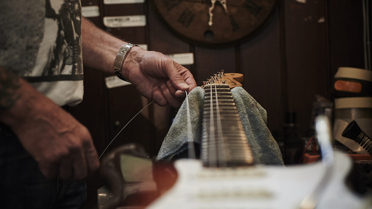 Closeup of hands stretching new guitar strings on a Fender Stratocaster