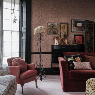 skirting board colour ideas, Victoria style living room with dark pink wallpaper, sofa and armchair, black woodwork and skirting, lace curtains, vintage artwork