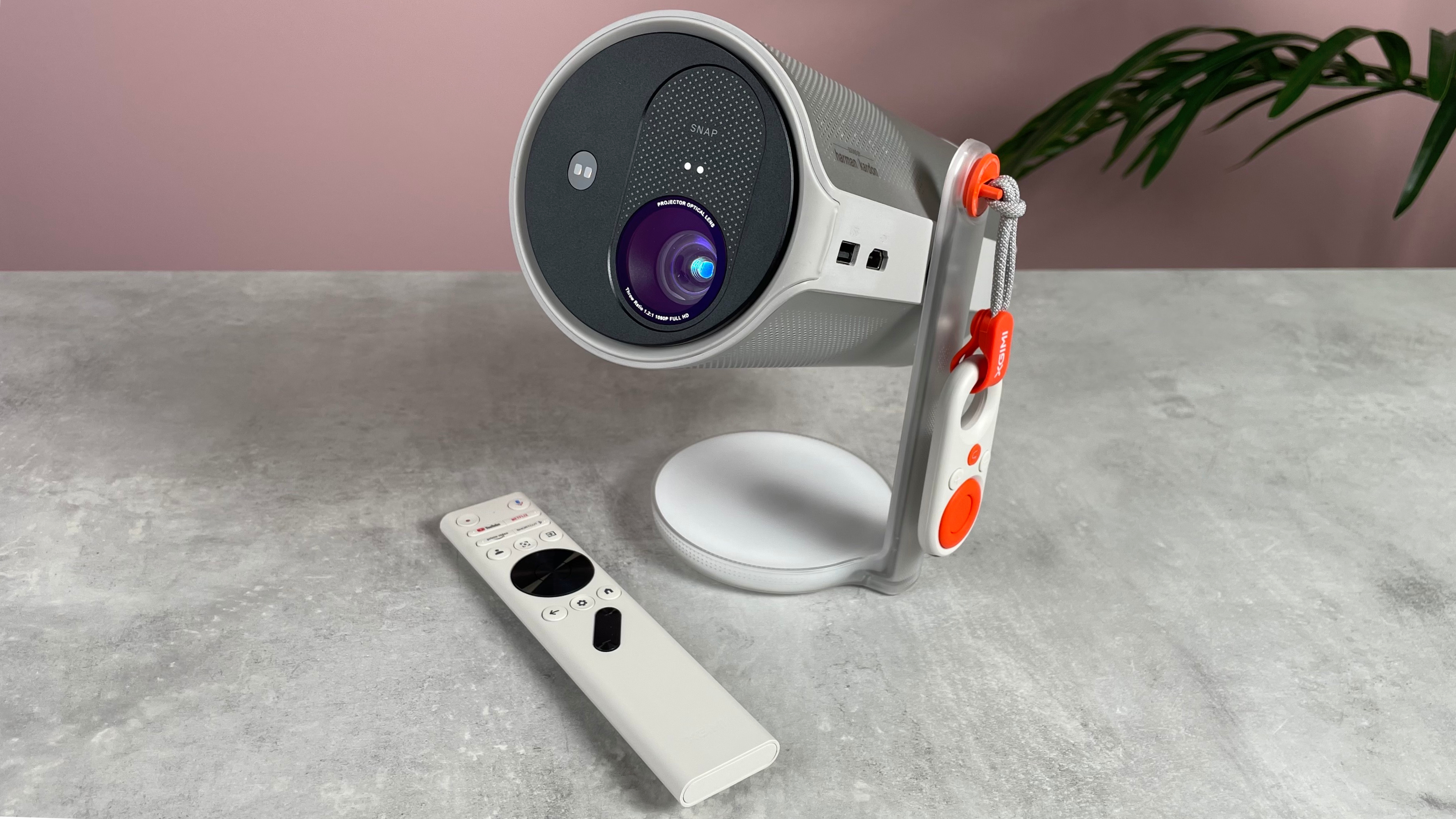 The XGIMI Mogo 4 is powered on, with its white remote in front of it, on the table.