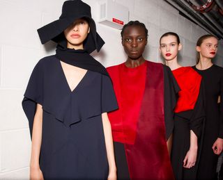 Models wearing fluid black dresses with startling flashes of red and loose trousers