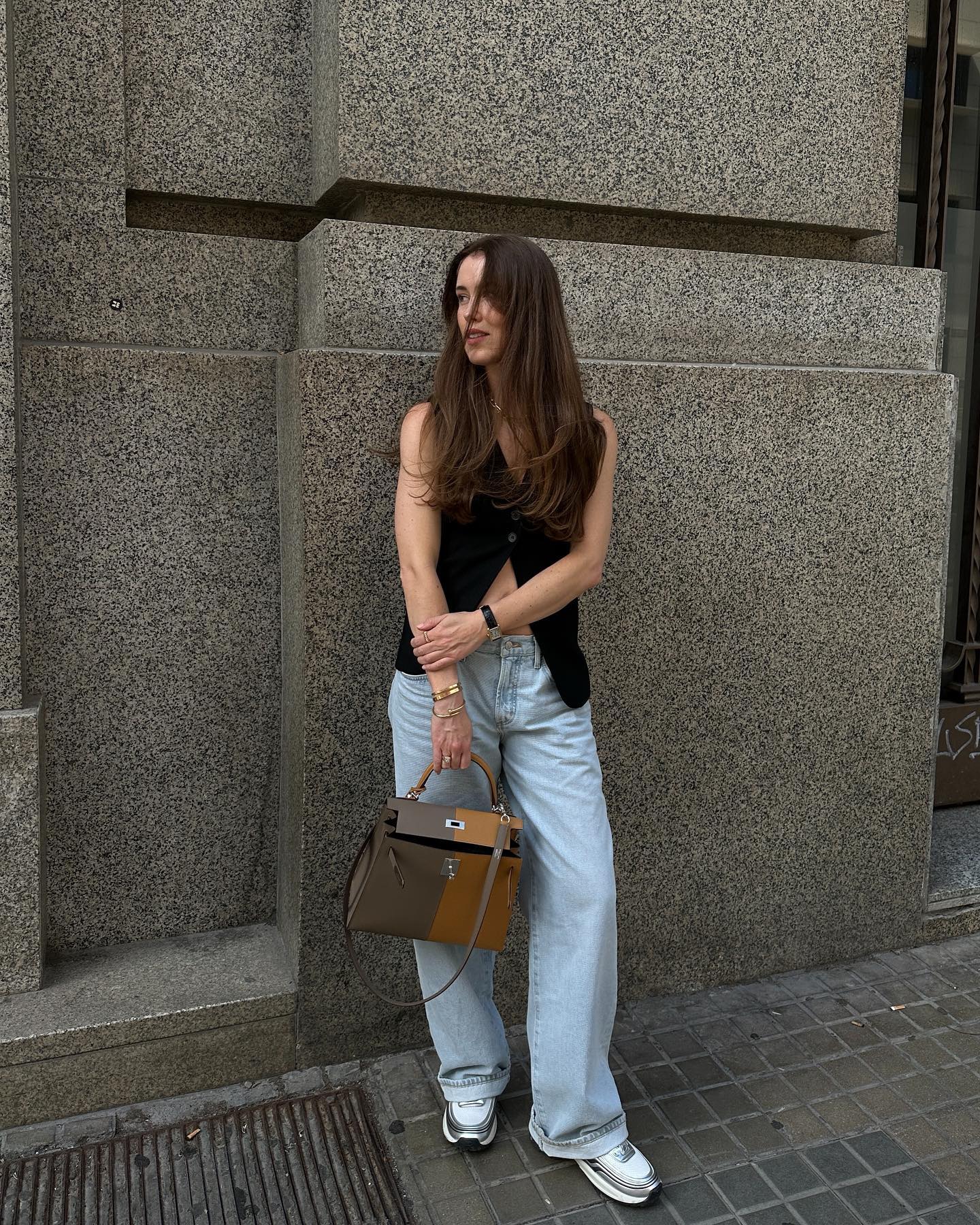 Girl wearing black vest with low-rise jeans and sneakers