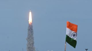 chandrayaan-3 launching into blue sky with the indian flag to the right of the image.