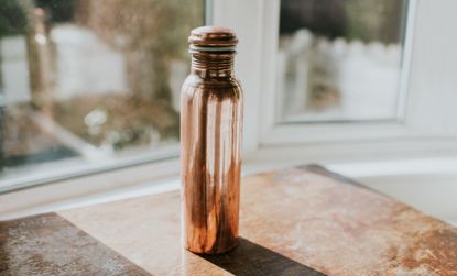 Tall copper water bottle with liquid from the snake juice diet inside.