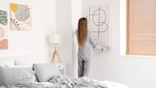 Someone hanging artwork in a bedroom